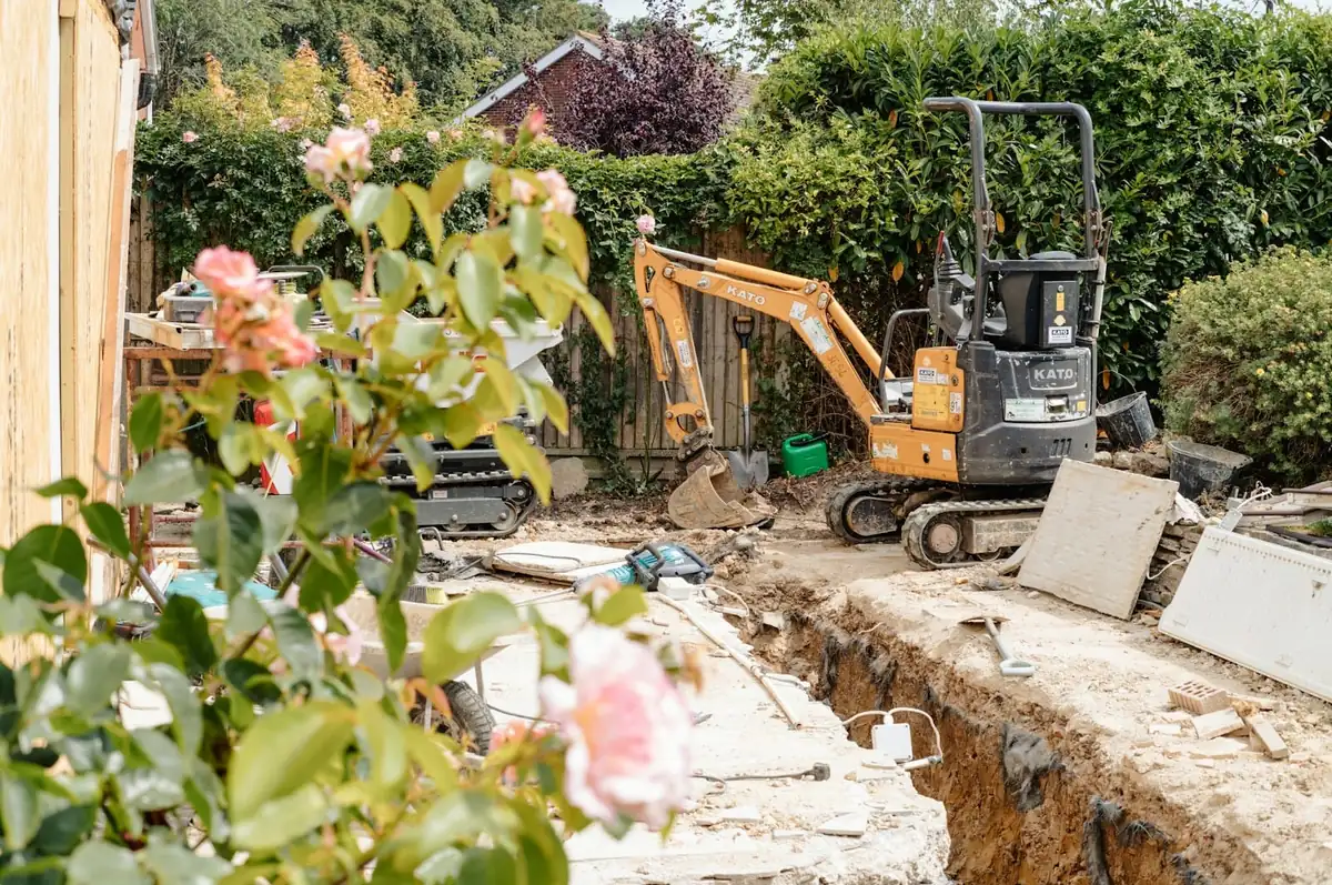 A mini digger beside a footing trench in a back garden